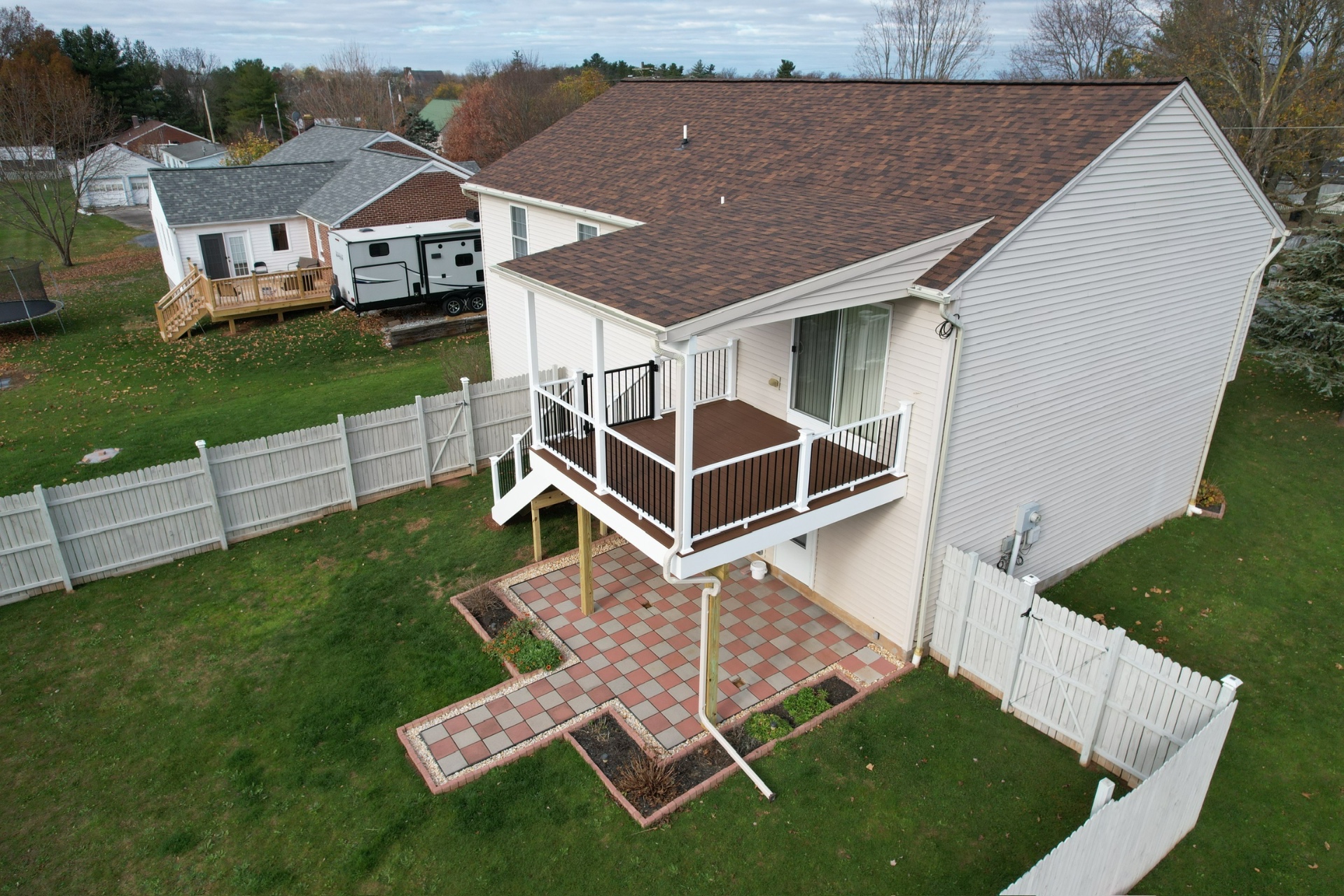 Two-story covered deck with composite flooring and white railings — Caliber Build · 01