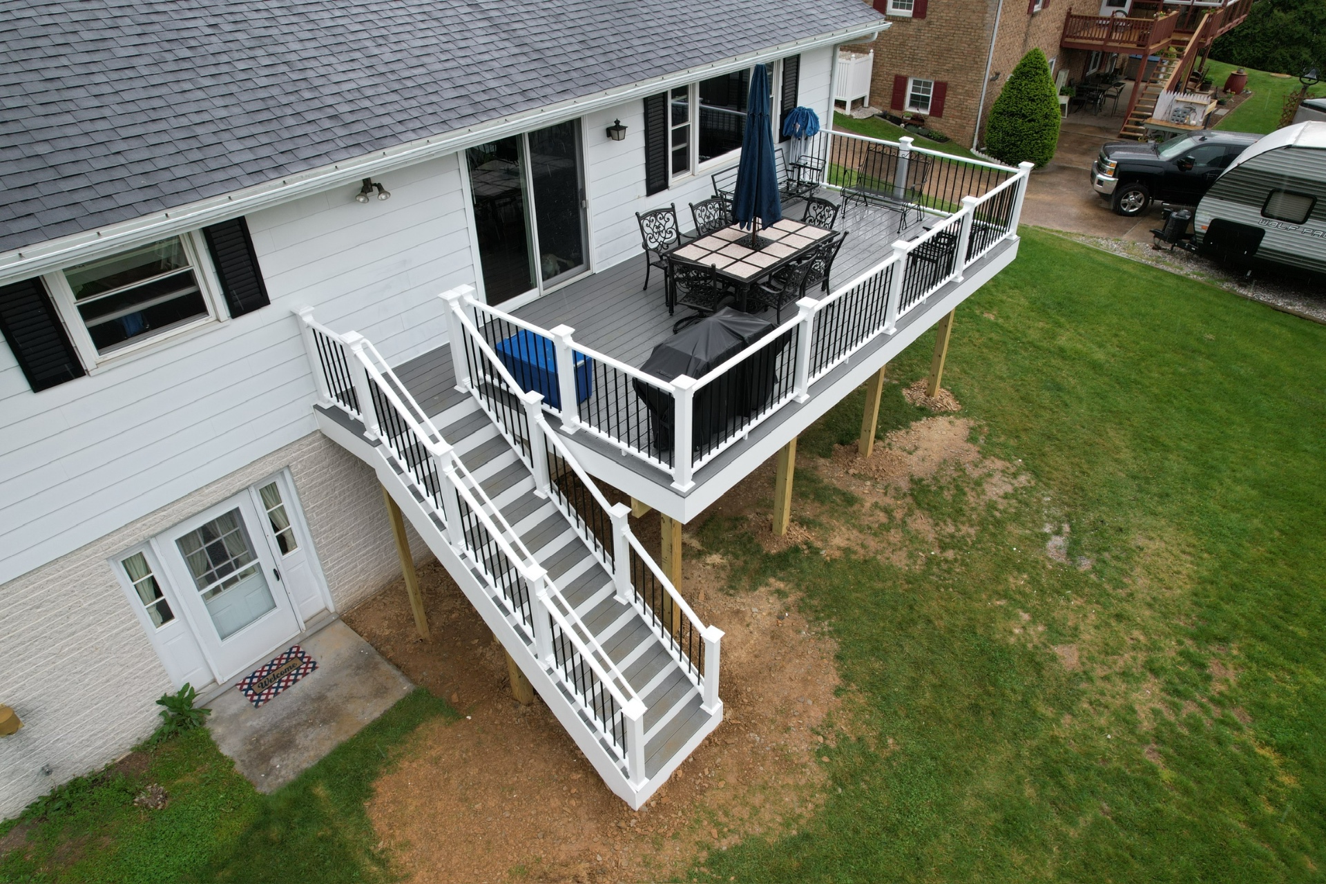 Gray composite deck with white railings and outdoor seating — Caliber Build · 04