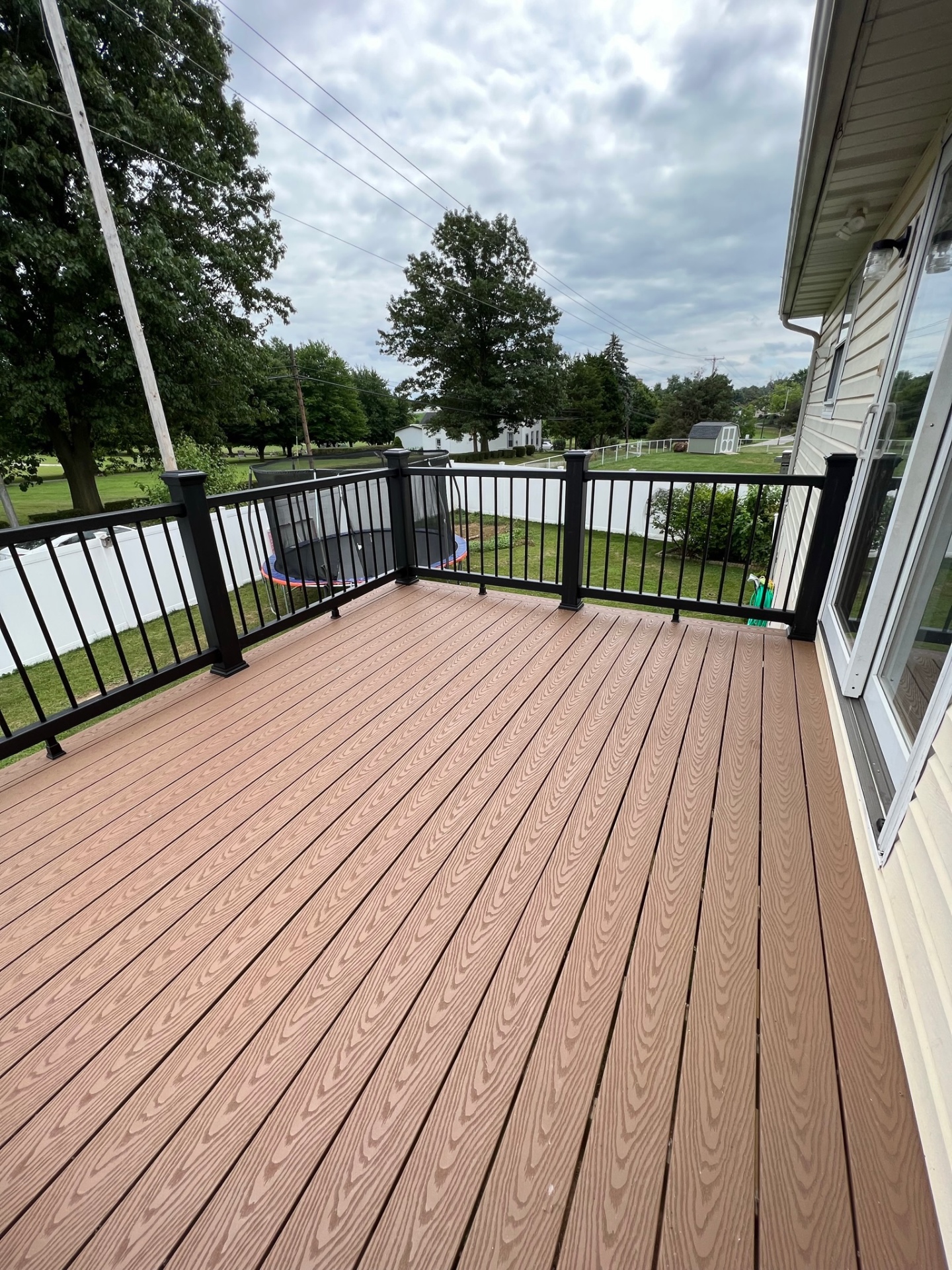 Cedar-tone composite deck with black aluminum railings — Caliber Build · 06